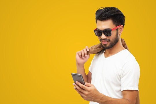 Asian business man handsome man with a mustache, smiling and laughing and using smart phone on yellow background