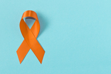 Orange ribbon on blue background . Healthcare and medicine concept. Multiple Sclerosis awareness. Leukemia awareness. Empty text space. - Powered by Adobe