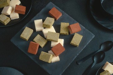 Assortment of soft chocolates on a black background with copy space. Milk and matcha Japanese gourmet chocolate close-up