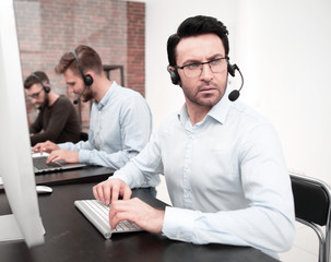serious businessman in a headset sitting at a Desk