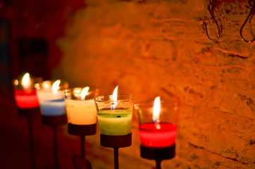Many candles burning at night, shallow depth of field, wall background