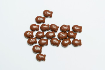 Cookies in the shape of fish. Small cookies covered with chocolate. Pastry on a white background. Dessert. Chocolate. Cookies laid out in the form of arrows.