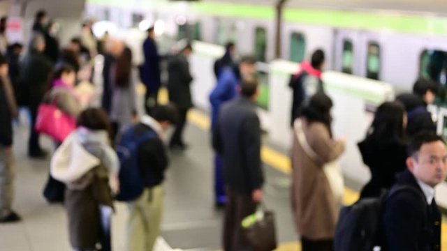 ホームに到着する電車と、それに乗り込む人々。