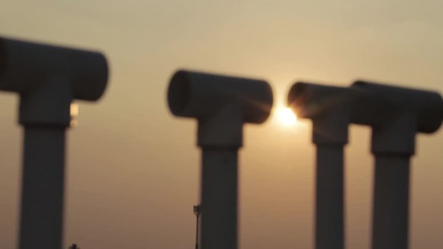 A pan up shot of sun through pipes with flares.