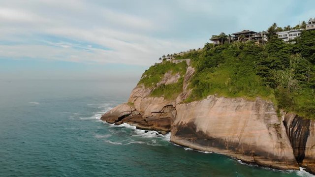 Closing in on the cliff rocks of Joatinga beach in Rio de Janeiro turning to reveal an island outside of the coast