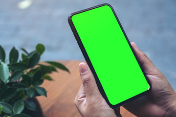 Mockup image of hands holding black mobile phone with blank white desktop screen
