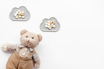 Childhood diseases concept. Treatment of children.Teddy bear toy and pills on white background top view copy space