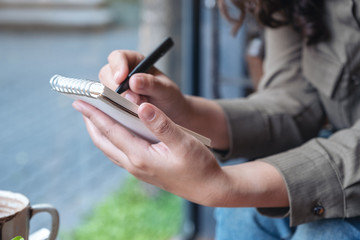 Closeup image of a woman's hands holding and writing on blank notebook