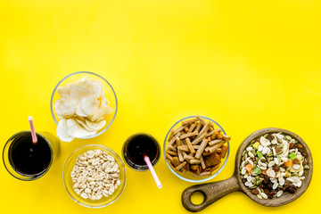 Snacks for TV watching. Chips, nuts, soda, rusks, dried fruits on yellow background top view copy space