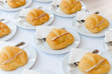 More fresh croissant sandwich with ham and cheese on white plate. tea time and coffee break at conference meeting business