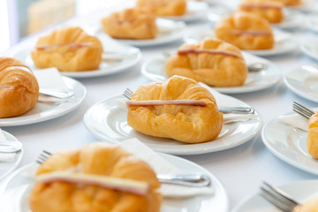 More fresh croissant sandwich with ham and cheese on white plate. tea time and coffee break at conference meeting business