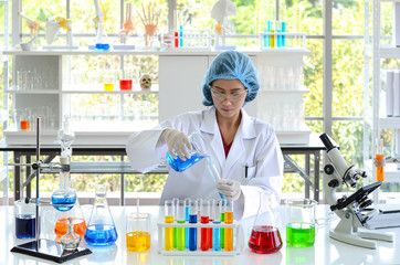The woman scientist researcher in laboratory holding a liquid solution and pouring to test tube in a lab.