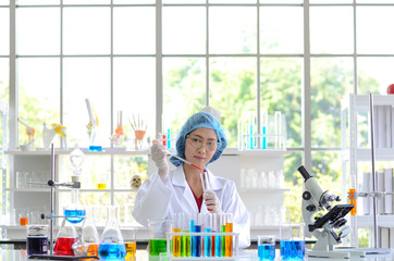 The woman scientist in laboratory doing experiments by Synthesising Compounds with use of dropper in a test tube.