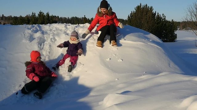 Mother with children playing in snow. Family walking and getting fun on winter sunny day