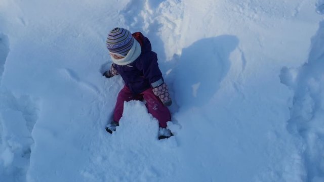 Child walking on winter day, kid getting fun jumping in deep snow on sunny day