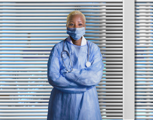 attractive and confident black African American medicine doctor wearing face mask and blue scrubs...
