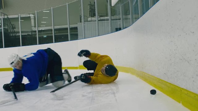 Track out shot of professional hockey player bumping into his opponent and pressing him to arena's barrier to take puck away