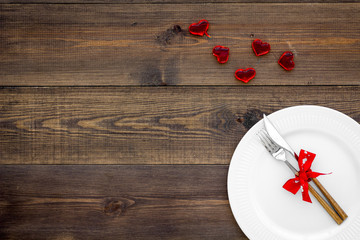 Dating in the restaurant on Valentine's day. Decorated dishes on dark wooden background top view copy space