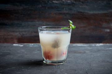 Old fahioned lychee cocktail on the rustic background. Selective focus. Shallow depth of field. 