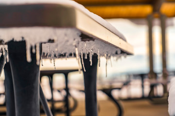 A snowy outdoor table with icicles underneath