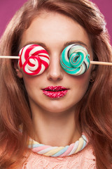 Beautiful pink lips with a sweet candy lollypop. Close up portret of young woman with candy in mouth.