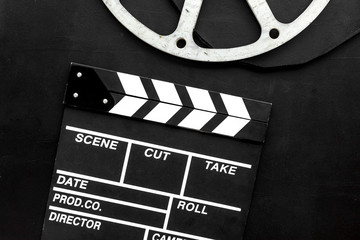 Filmings concept. Clapperboard and film stock on black background top view copy space