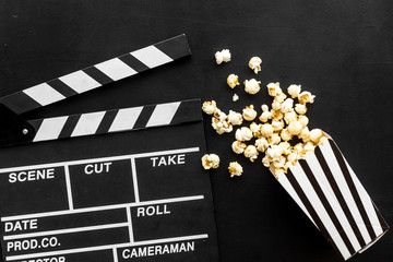 Film watching concept. Clapperboard and popcorn on black background top view