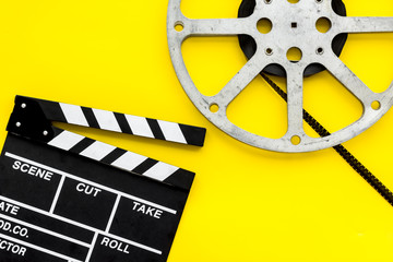 Filmings concept. Clapperboard and film stock on yellow background top view space for text