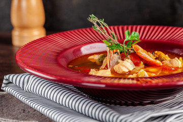 French cuisine concept. Classic French fish soup of seafood, shrimps, mussels, squid, potatoes, tomatoes. Beautiful serving dishes in the restaurant. copy space