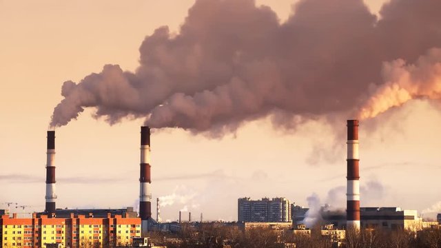 Air pollution from industrial and thermal plants in the city with pipes throwing smoke in the sky. Timelapse of industrial cityscape at winter sunset. 4K UHD 4096 x 2304 ultra high definition 