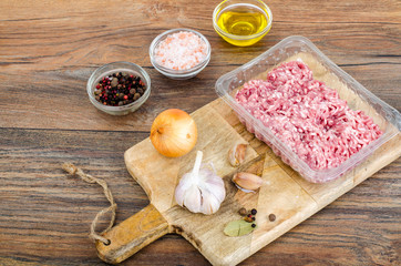 Raw minced meat with spices for cooking on wooden board