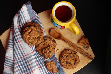 Cookies with chocolate chips and tea against dark background