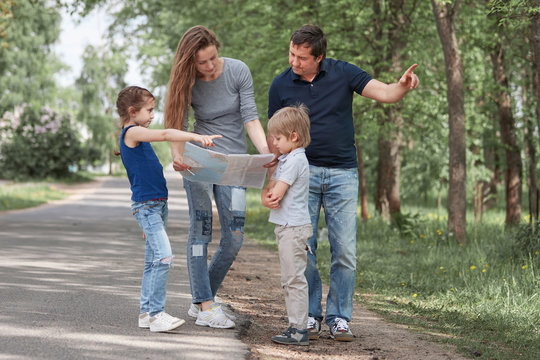 Family With A Road Map Standing On The Side Of The Road. F