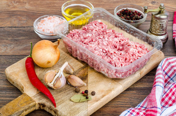Raw minced meat with spices for cooking on wooden board