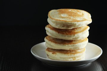 A stack of freshly backed pancakes and a cup of coffee