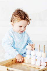 Child boy playing in his room with a wooden toy sorter. Smiling cute boy with  natural toys.