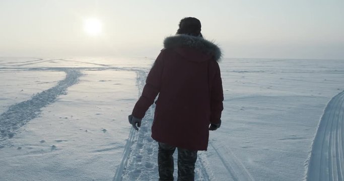 Young traveller goes through a blizzard at beautiful sunset. Polar expedition