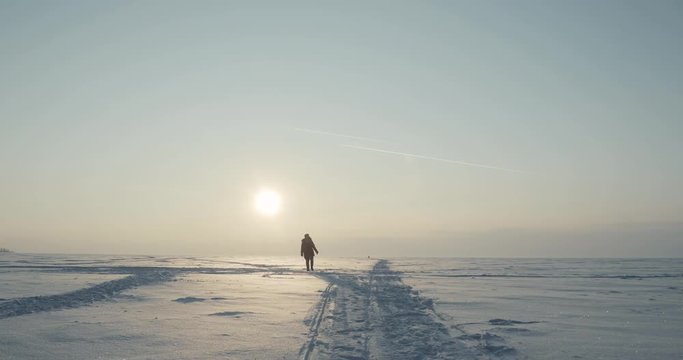 Young traveller goes through a blizzard at beautiful sunset. Polar expedition