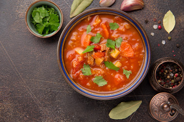 Thick tomato soup with meat, cereals and vegetables. Traditional Oriental cuisine, spicy stew with beef or lamb, rice and spices. Food on dark background