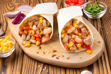 Burrito in tartilla with meat, vegetables, white beans, red pepper, corn. Delicious lunch, Mexican food, homemade snack