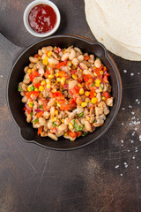 Preparation of filling for burritos in tortillas with meat, vegetables, white beans, red pepper, corn. Delicious lunch, Mexican food, homemade snack