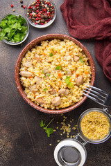 Bulgur with turkey, pork or beef. Eastern dish of rice, delicious traditional food. Stewed meat with grits. Pilaf on dark background