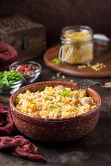 Bulgur with turkey, pork or beef. Eastern dish of rice, tasty traditional food. Stewed meat with grits. Pilaf on dark background