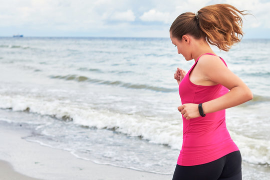 Athletic woman running on sea beach, copy space. Female runner working out at summer morning. Healthy lifestyle concept