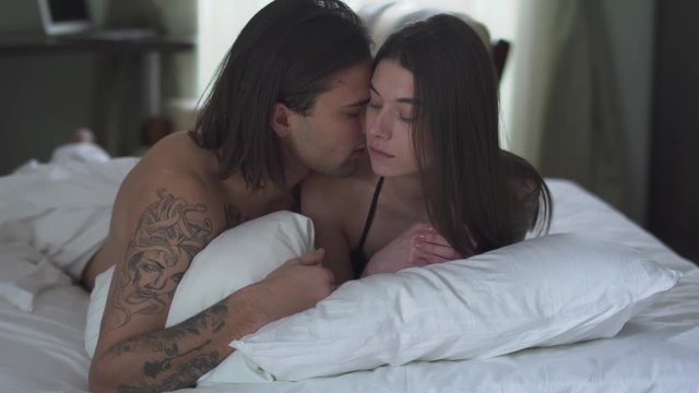 Portrait sensual tender young couple lying in bed kissing passionately. Romantic relationship of beutiful couple