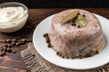 Jellied aspic with chicken meat, traditional Russian dish holodets on dark wooden background.