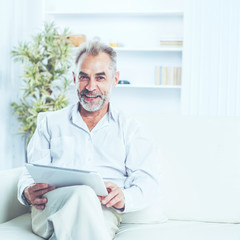 confident businessman with digital tablet sitting on sofa in bright office