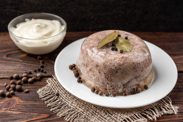 Jellied aspic with chicken meat, traditional Russian dish holodets on dark wooden background.