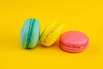 Sweet almond colorful macaron or macaroon dessert cake isolated on trendy yellow pastel background. French sweet cookie. Minimal food bakery concept. Flat lay copy space