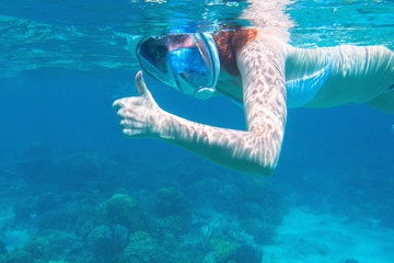 Red hair woman snorkeling undersea. Snorkel show thumb up under water. Woman in full-face snorkeling mask